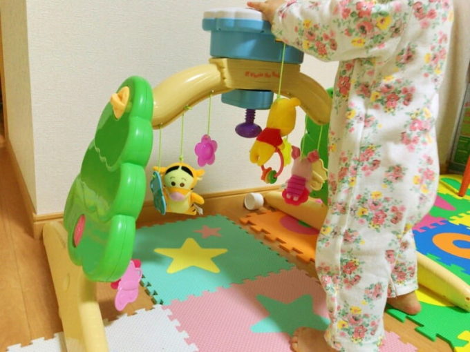 床に置いたメリーにつかまり立ちする子供